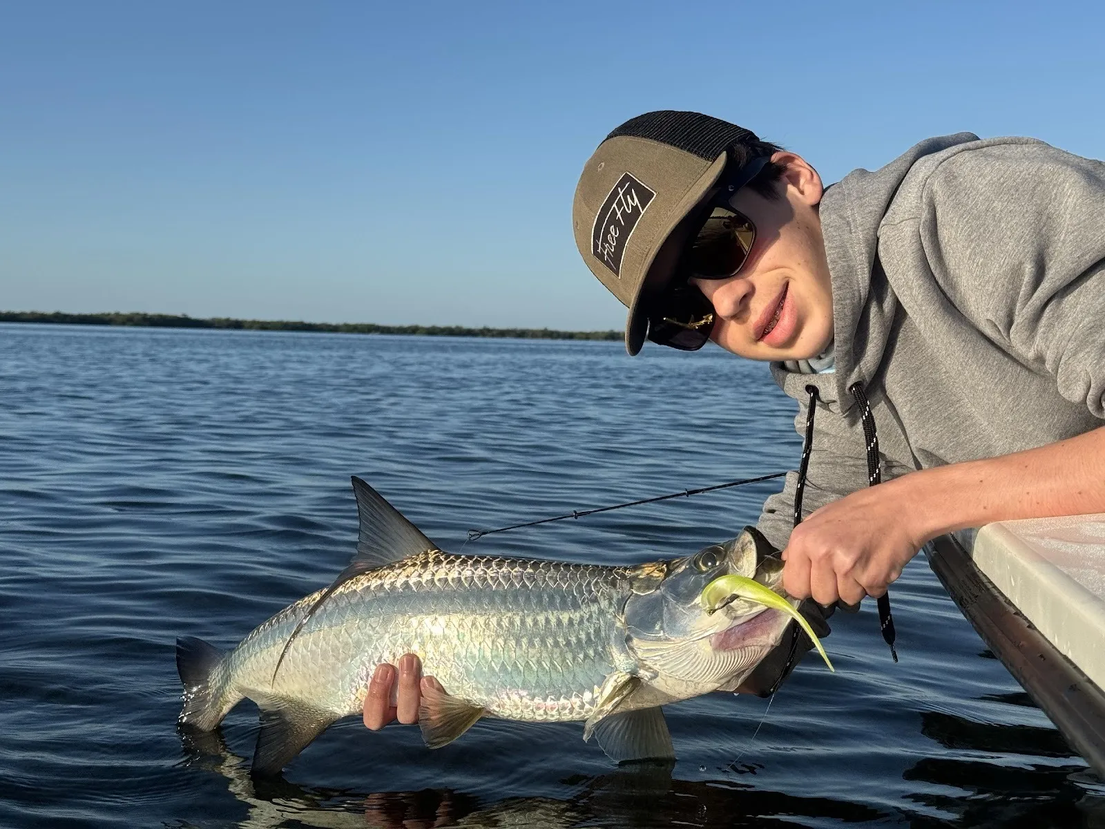 Young angler holding a tarpon boatside