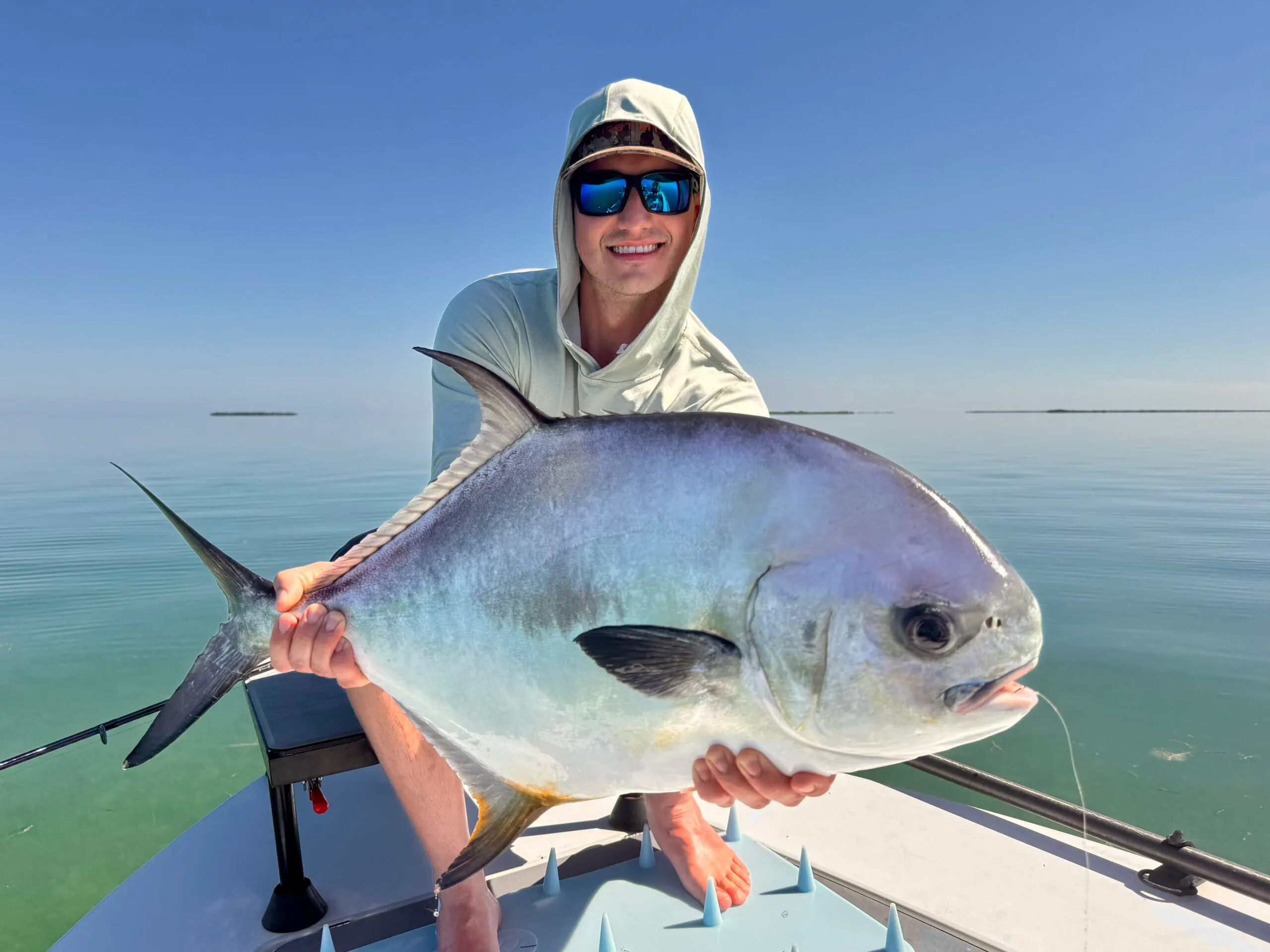 Angler holding a permit on the deck of the skiff